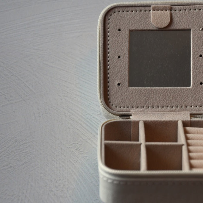 Beige jewelry box with compartments on a gray surface