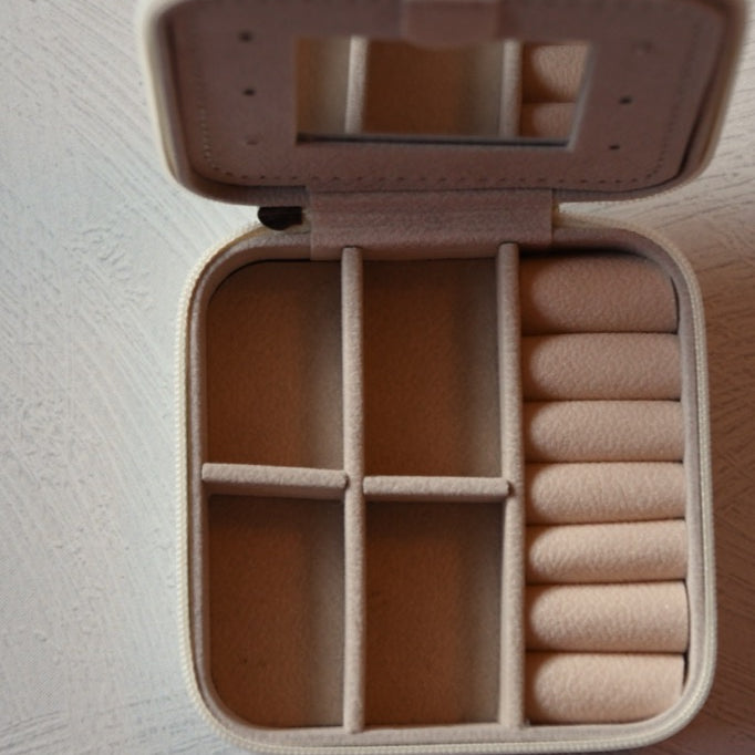 Beige jewelry box with compartments on a light gray surface
