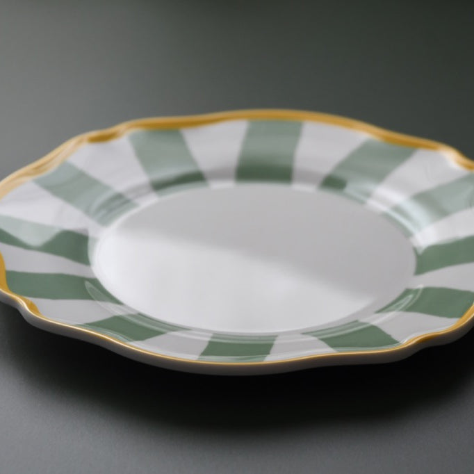 Ceramic plate with green and gold decorative rim on a gray background