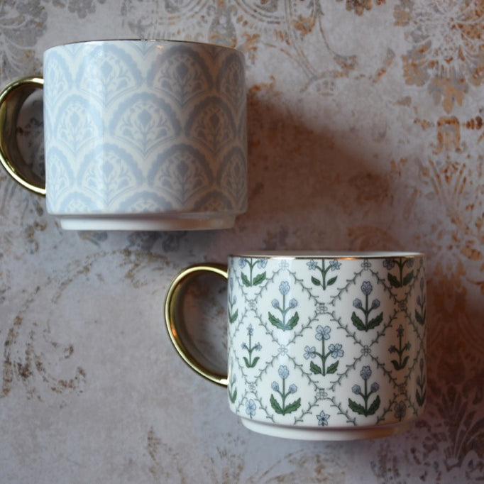 Two patterned mugs on a textured surface