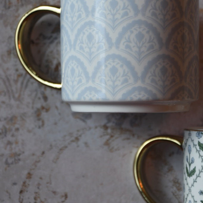 Patterned mug with gold handle on a textured surface