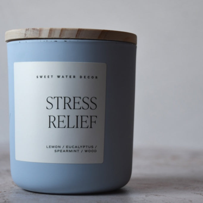 Candle labeled 'Stress Relief' with a wooden lid on a neutral background