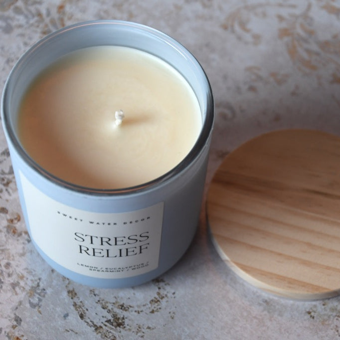 Candle in a tin labeled 'Stress Relief' on a textured surface
