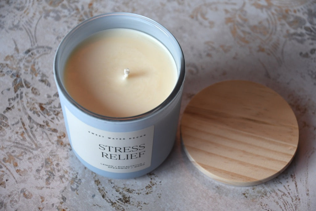 Candle in a tin labeled 'Stress Relief' on a textured surface