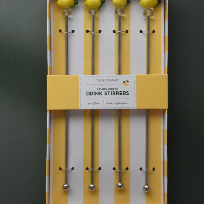 Set of drink stirrers in a yellow and white striped box on a dark background