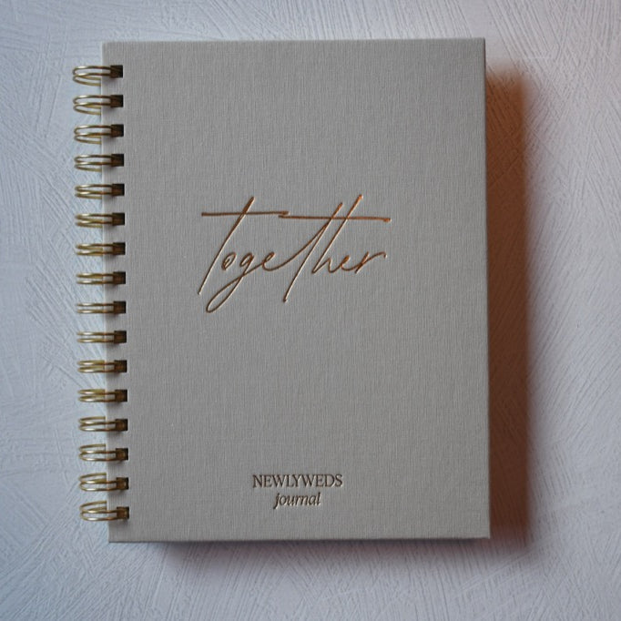 Notebook titled 'Together Newly Weds Journal' on a light gray background