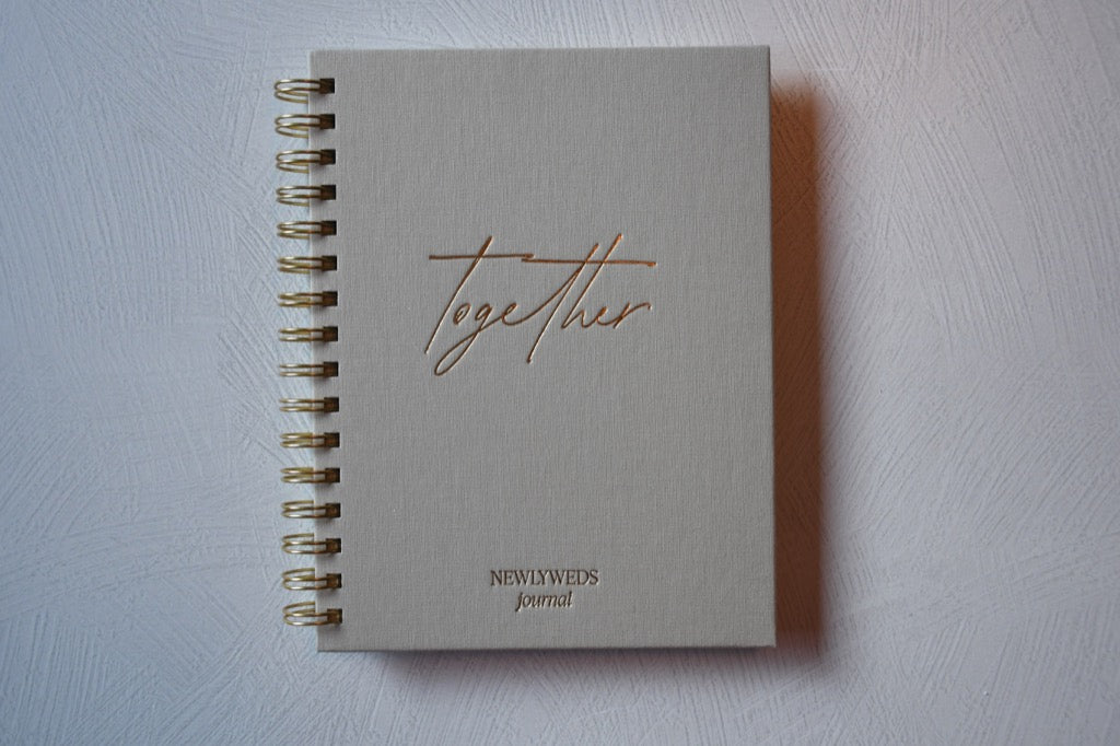 Notebook titled 'Together Newly Weds Journal' on a light gray background