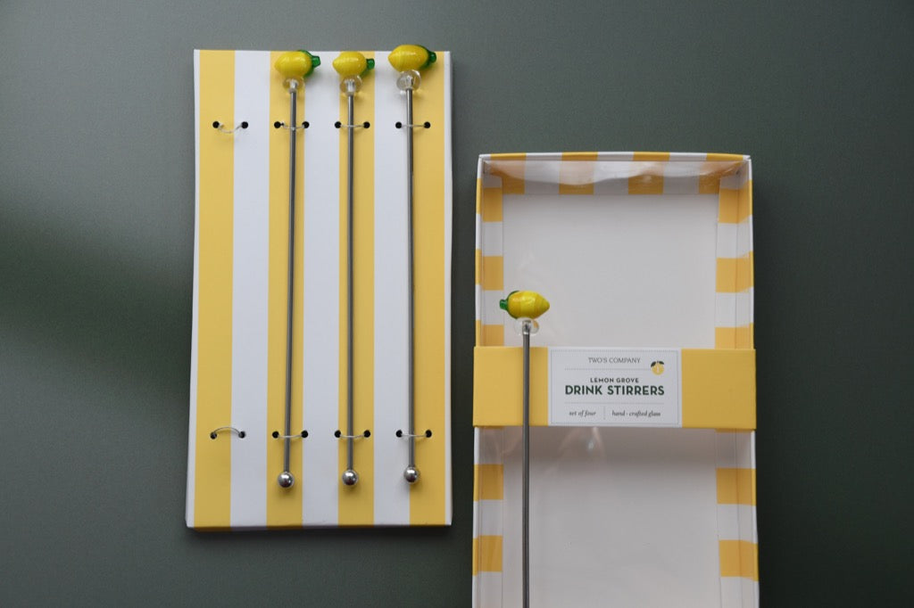 Packaging of lemon-themed drink stirrers with yellow and white striped design on a gray background.