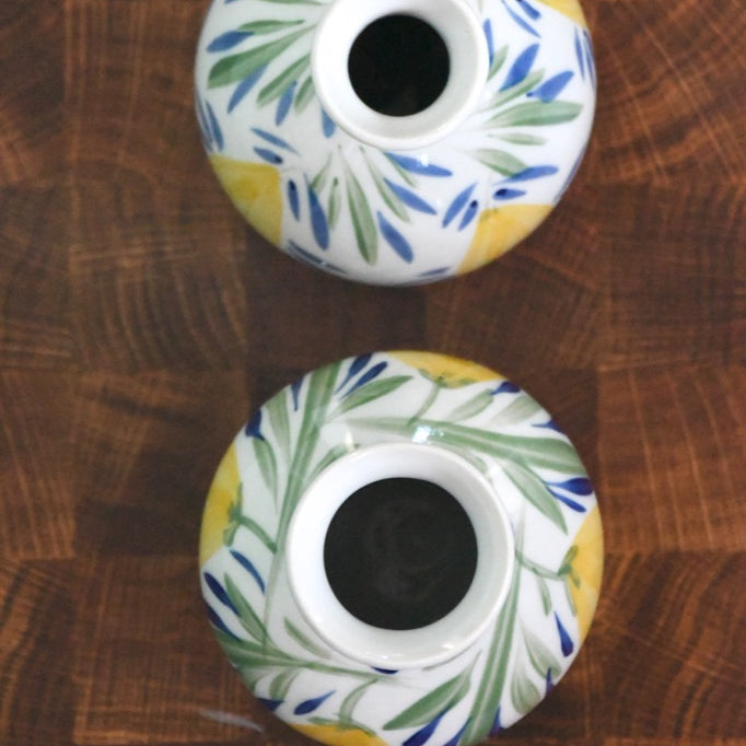 Two ceramic candle holders with floral patterns on a wooden surface