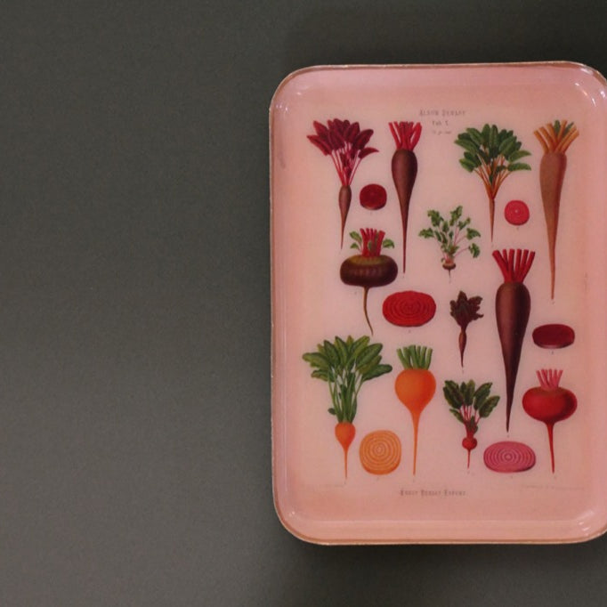 Peach tray with vegetable illustrations on a gray background