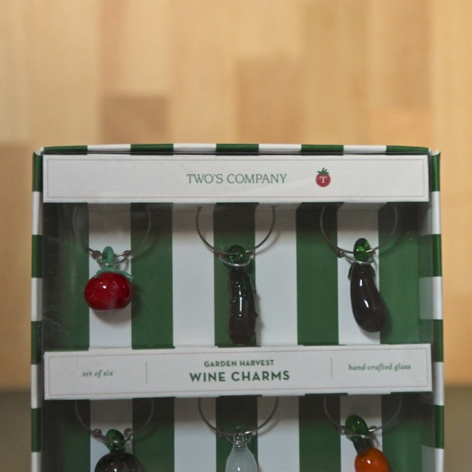 Two's Company Garden Harvest wine charms in a striped box on a wooden surface.