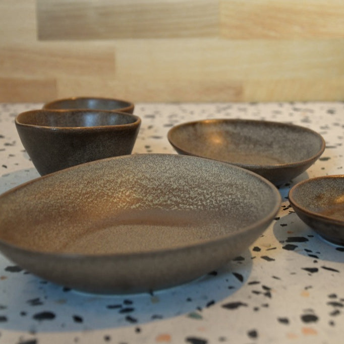 Set of four ceramic bowls on a speckled countertop with a wooden backsplash.