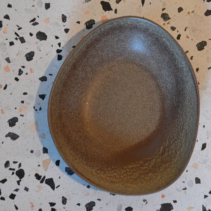 Brown ceramic plate on a speckled surface