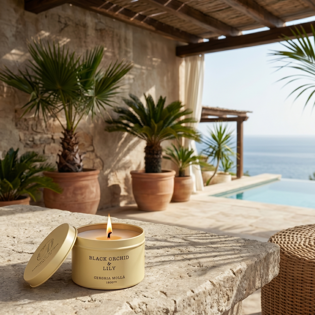 Candle labeled 'Black Orchid & Lily' on a stone surface with a scenic background of a pool and ocean.