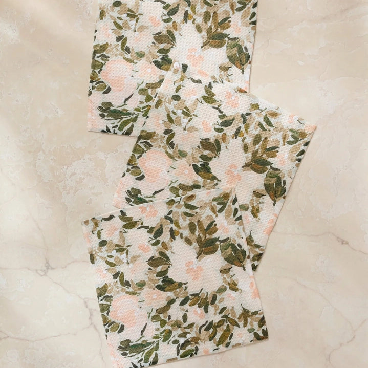 Two floral-patterned towels on a textured beige surface