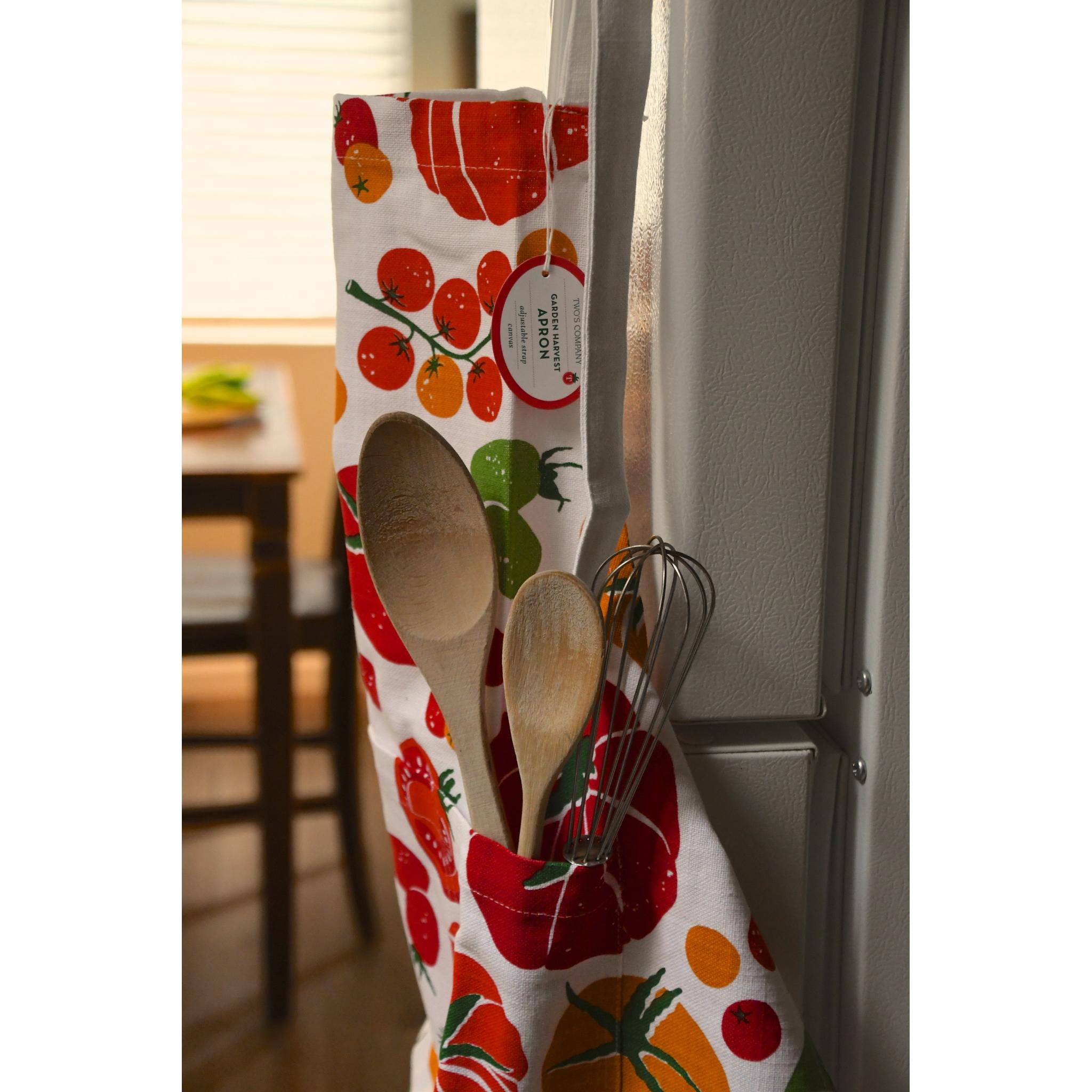 Kitchen towel with fruit pattern hanging on a refrigerator handle, with utensils attached.
