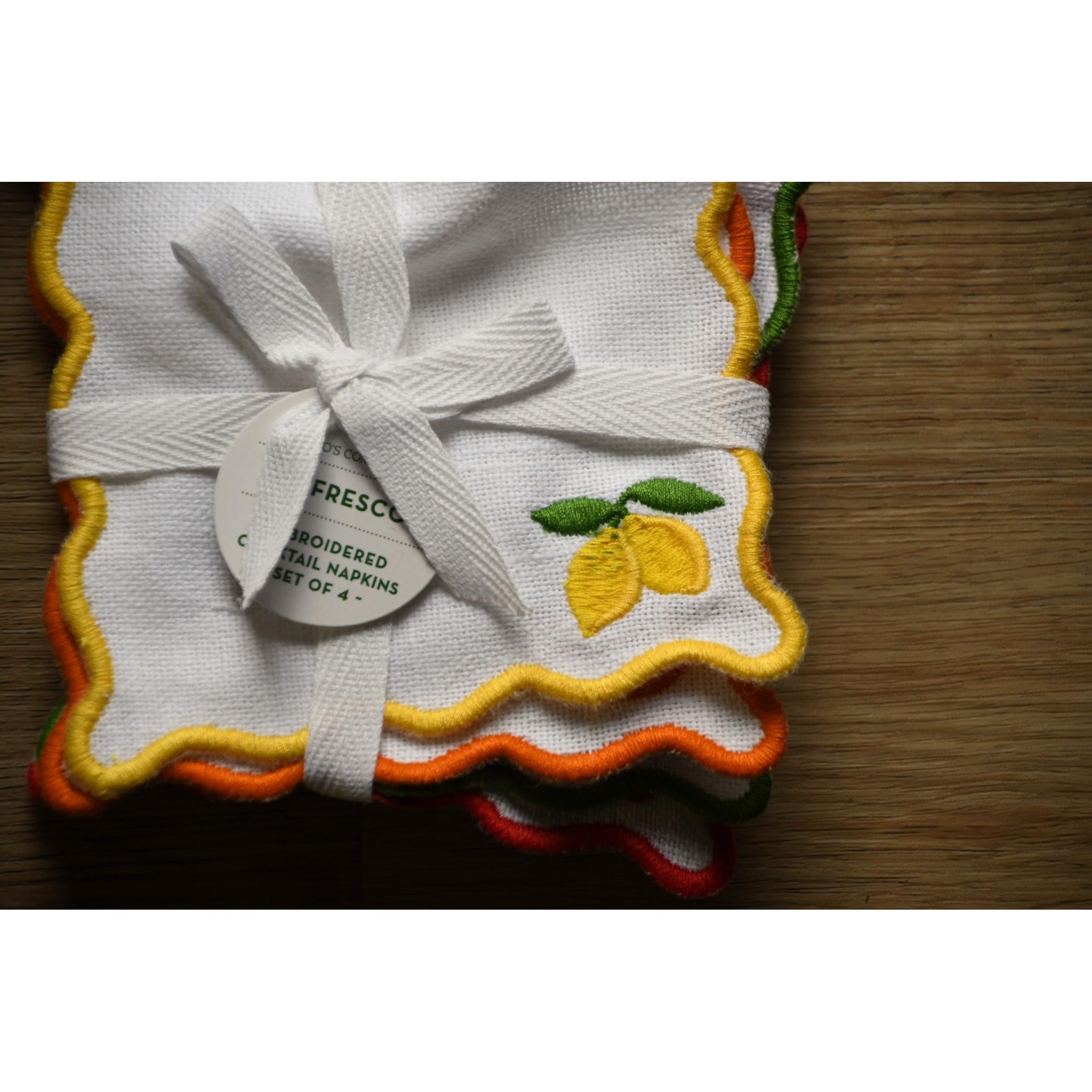 Set of embroidered napkins with lemon design on a wooden surface