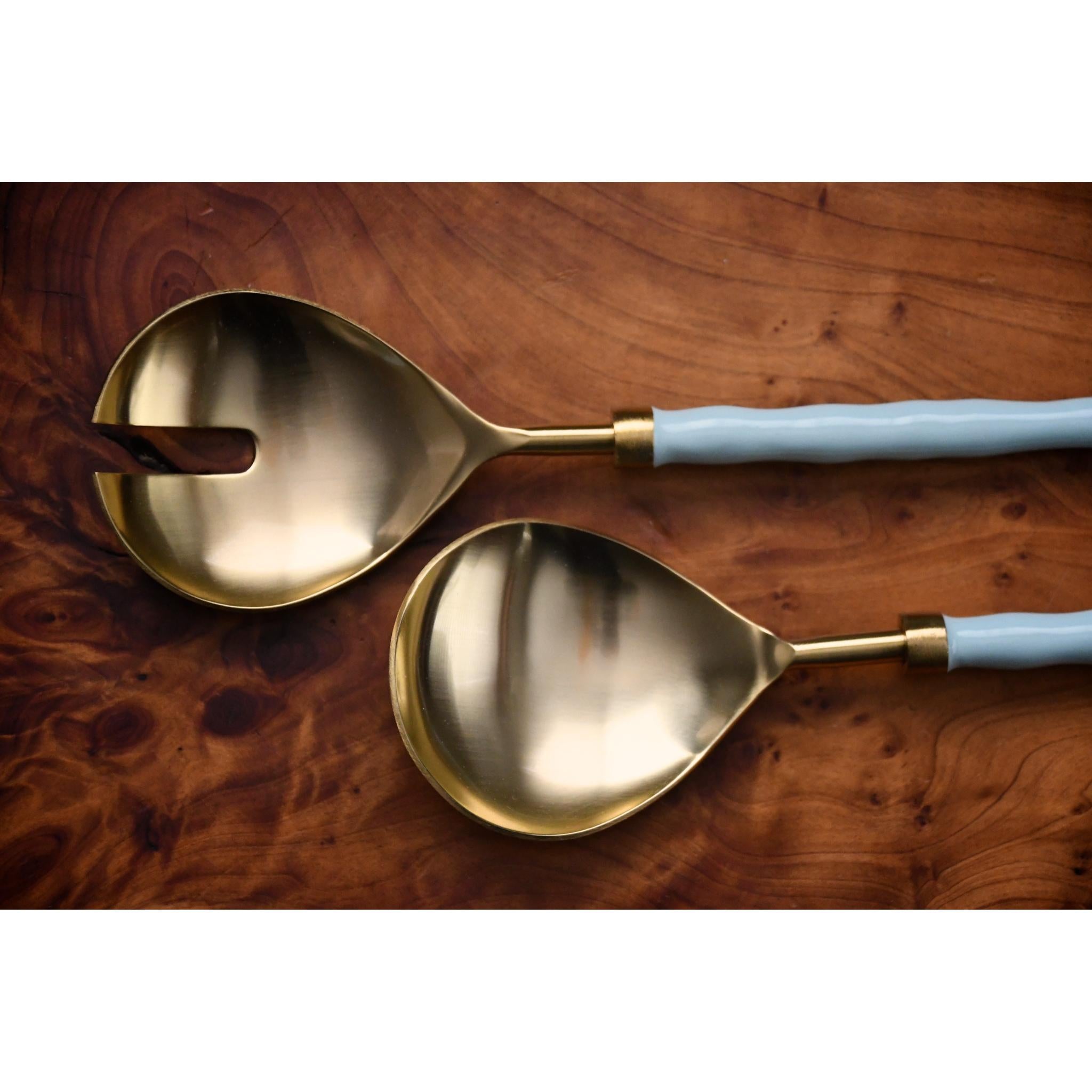 Two gold spoons with light blue handles on a wooden surface