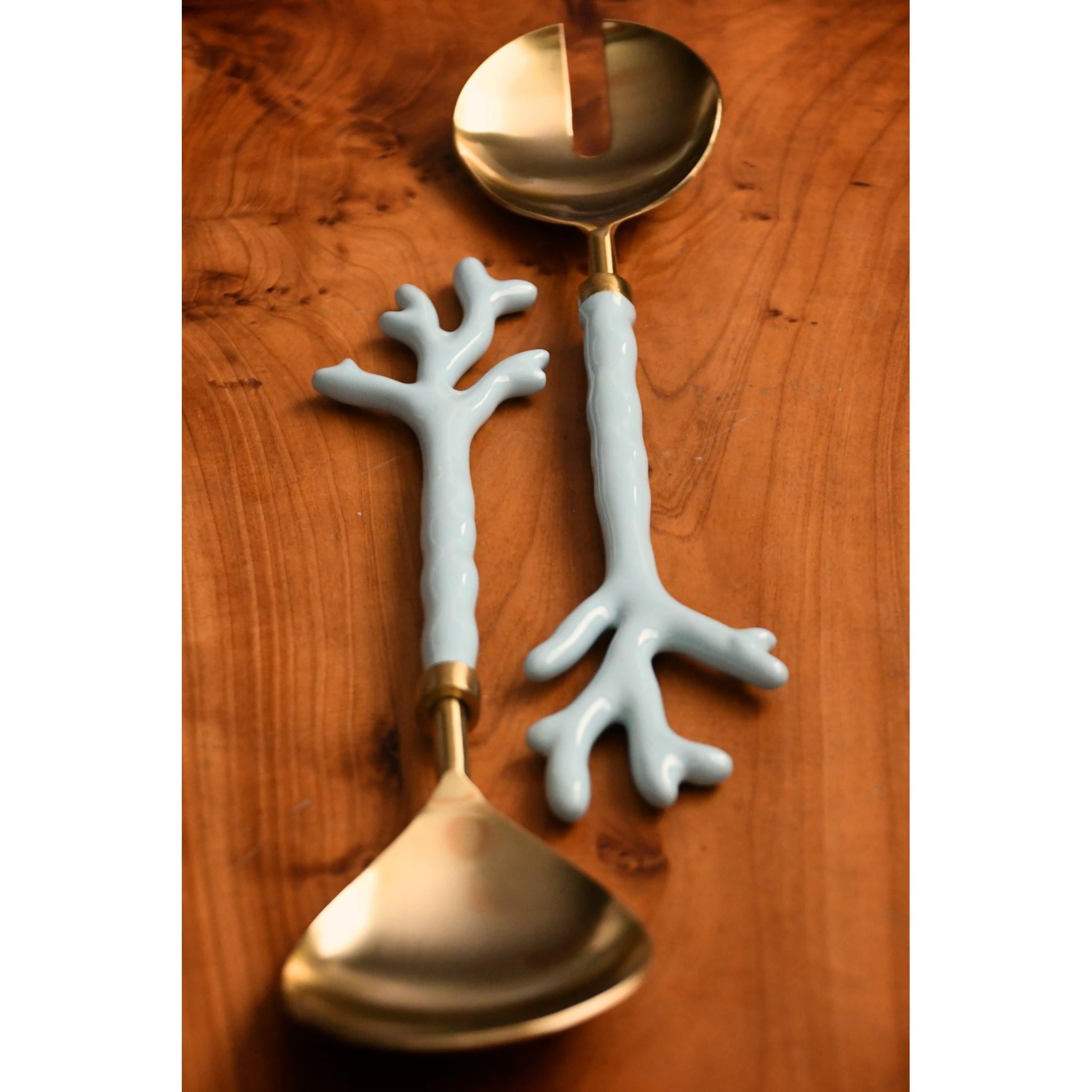 Two decorative spoons with coral-like handles on a wooden surface