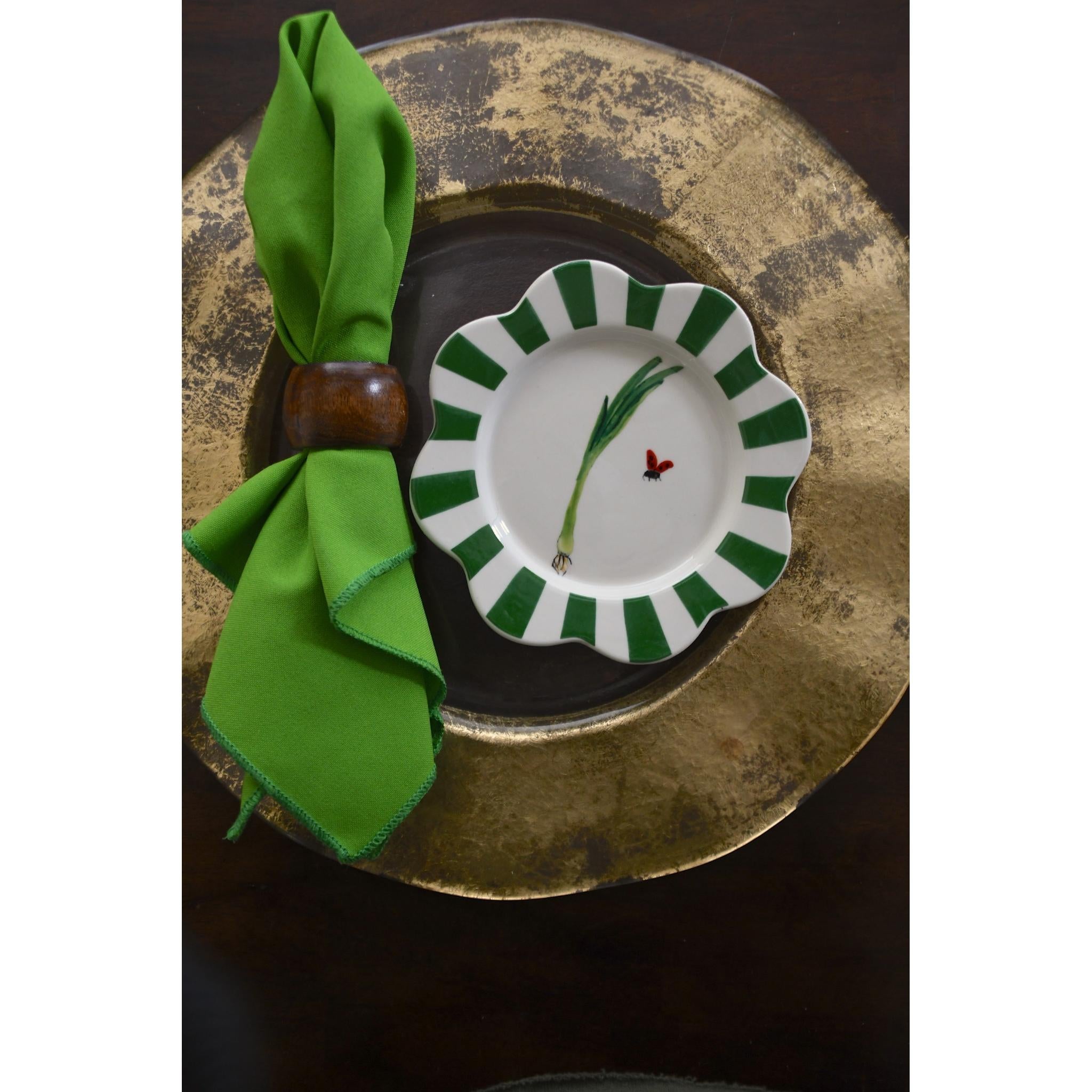 Decorative plate with green and white design on a gold tray with a green napkin.