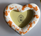 Heart-shaped frame with gold center and orange and white pattern on a ivory background