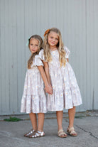 Childs dress with white flower print on a classic taupe dress. This dress is  feminine with flutter sleeves