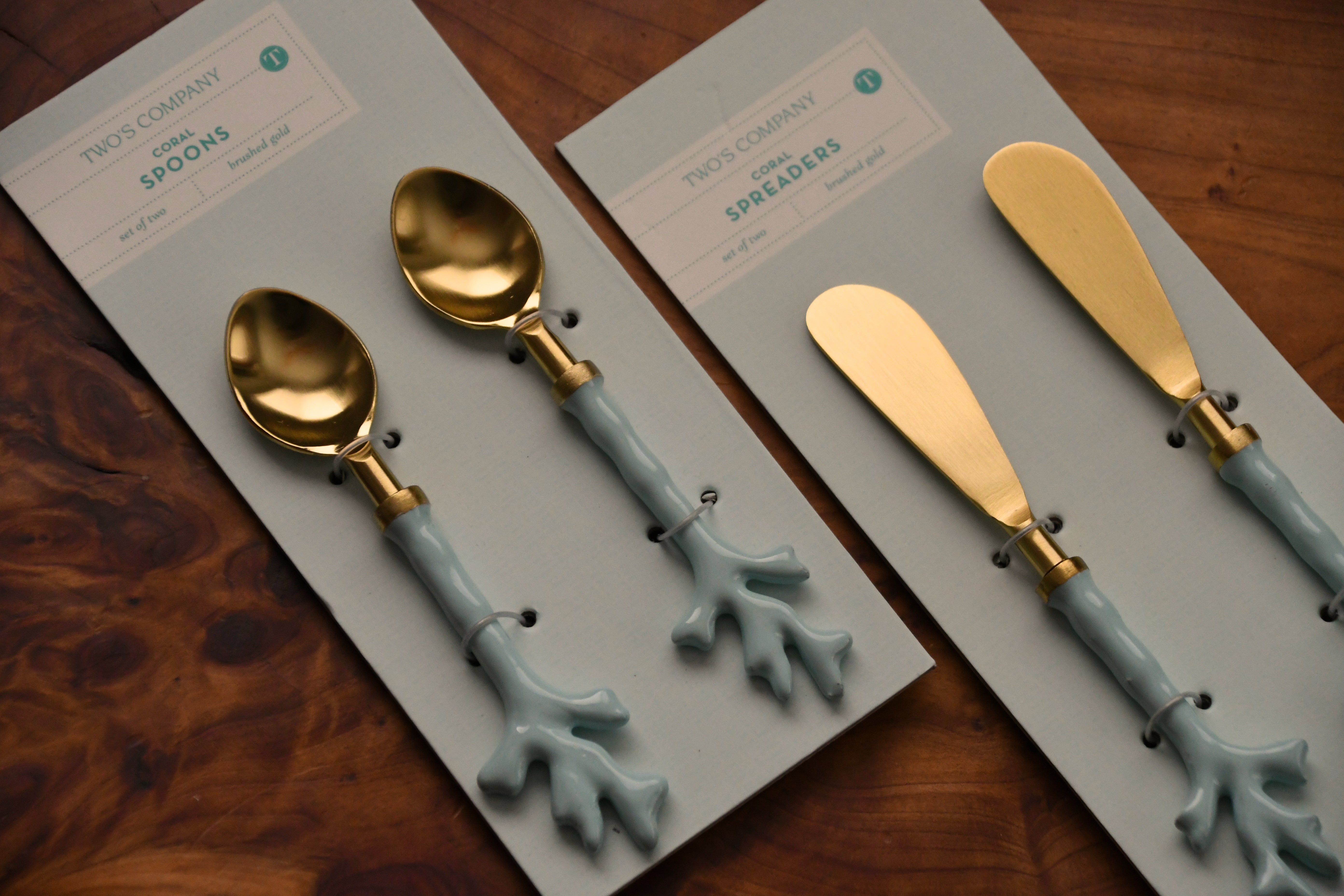 Set of gold and blue spoons and spreaders on branded cards on a wooden surface