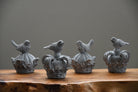 Decorative bird sculptures on crowns on a wooden surface with a gray background