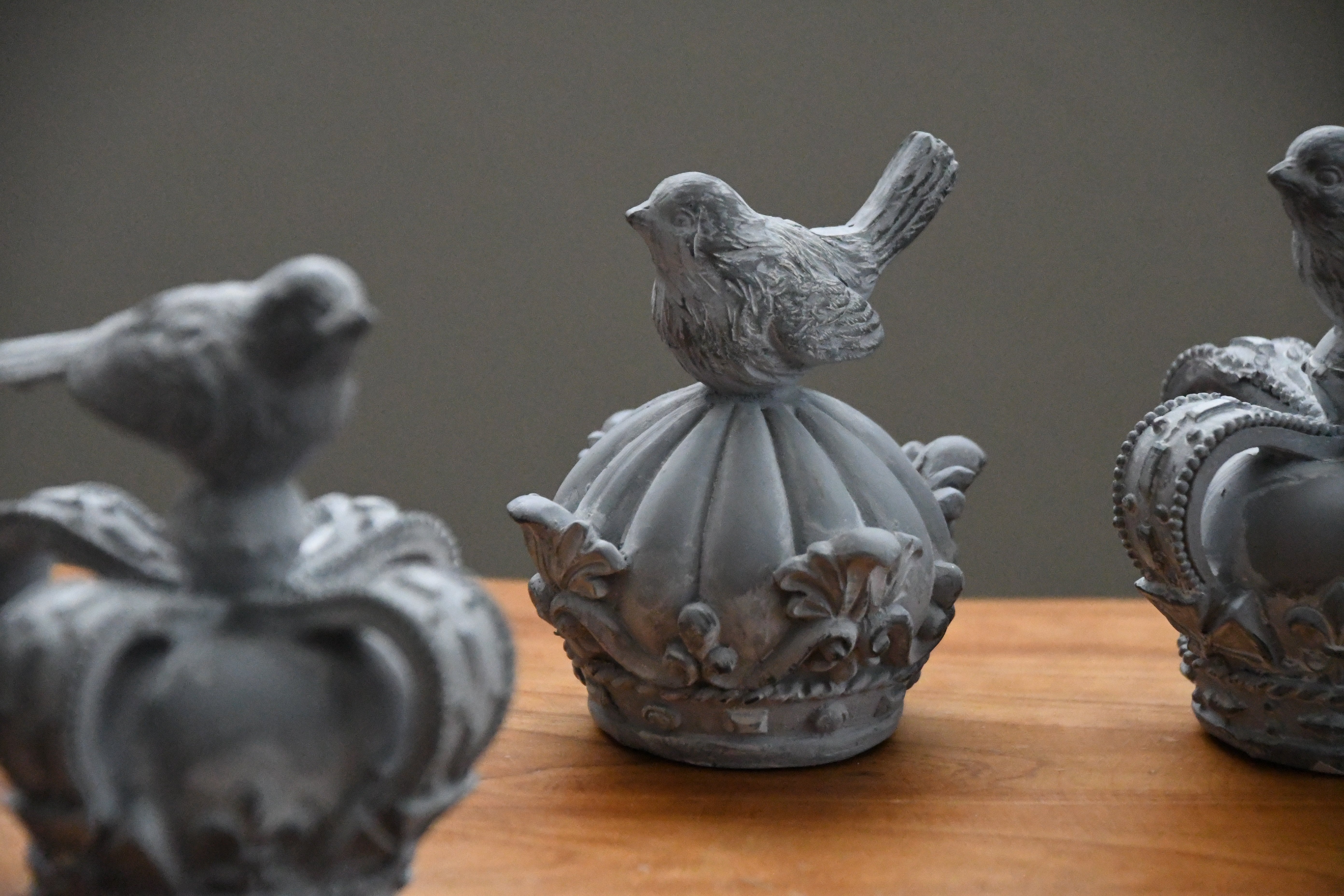 Decorative stone bird sculptures on a wooden surface with a neutral background