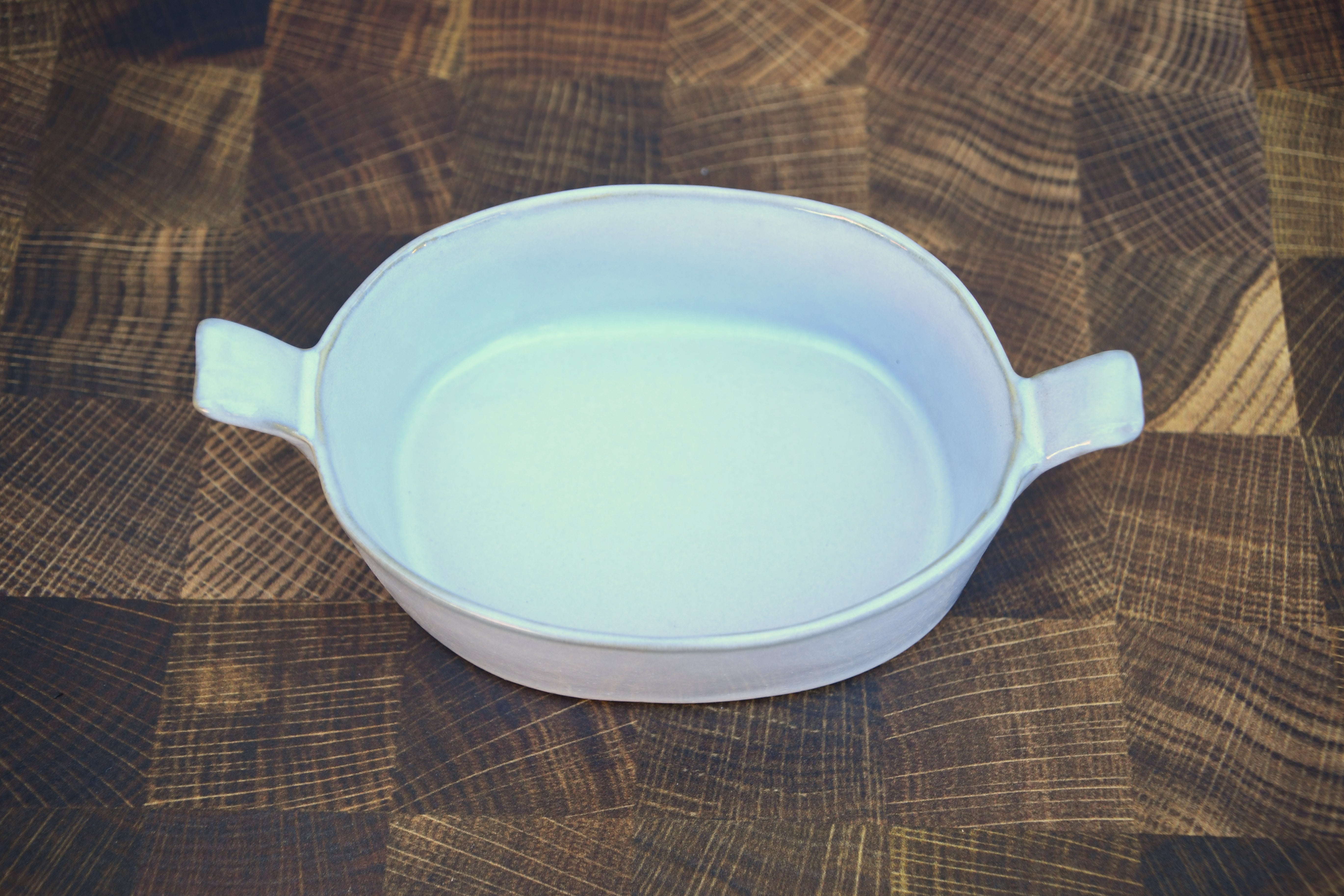 Stoneware baker with handles. White glaze. Dishwasher, oven and microwave safe.