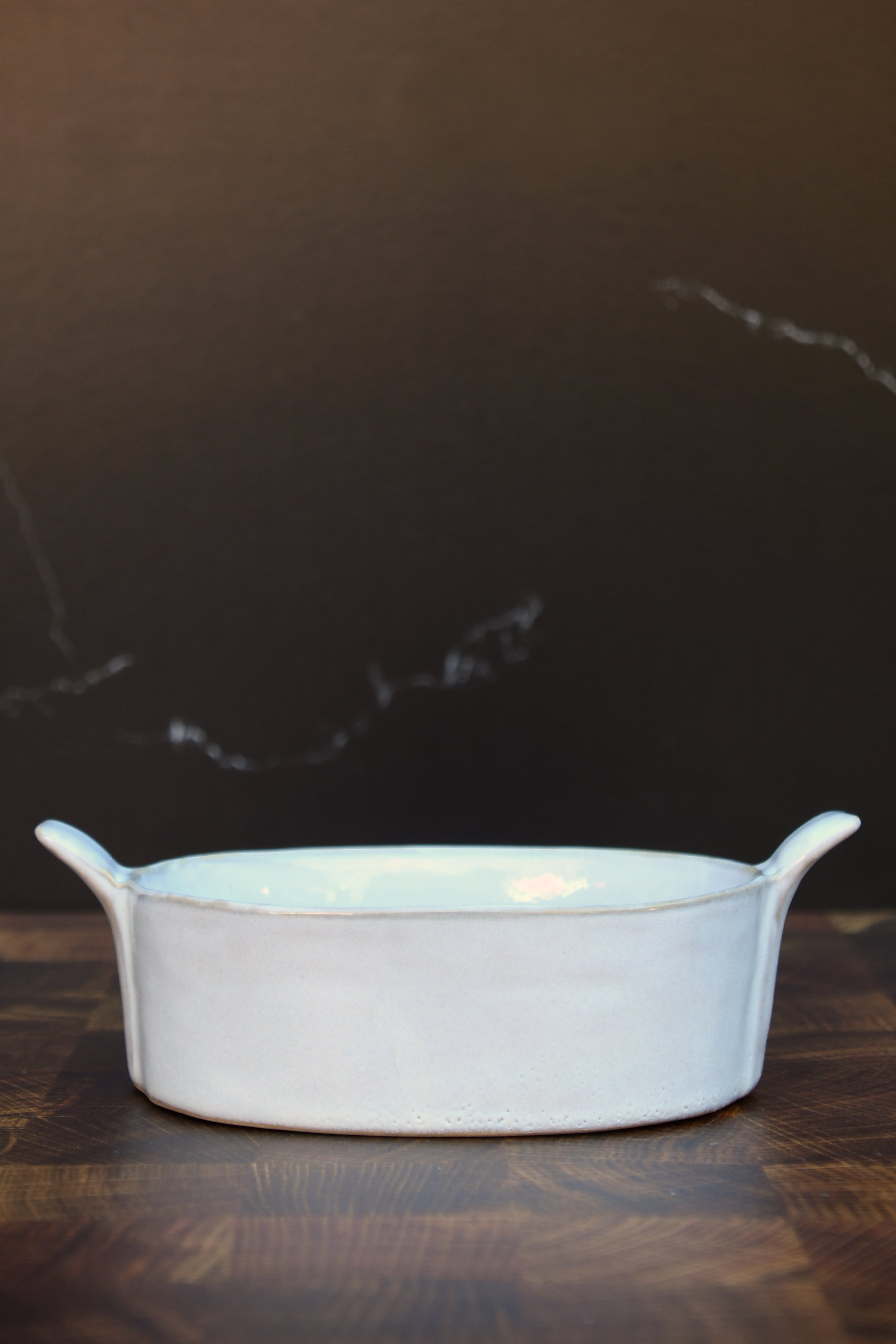 Stoneware baker with handles. White glaze. Dishwasher, oven and microwave safe.