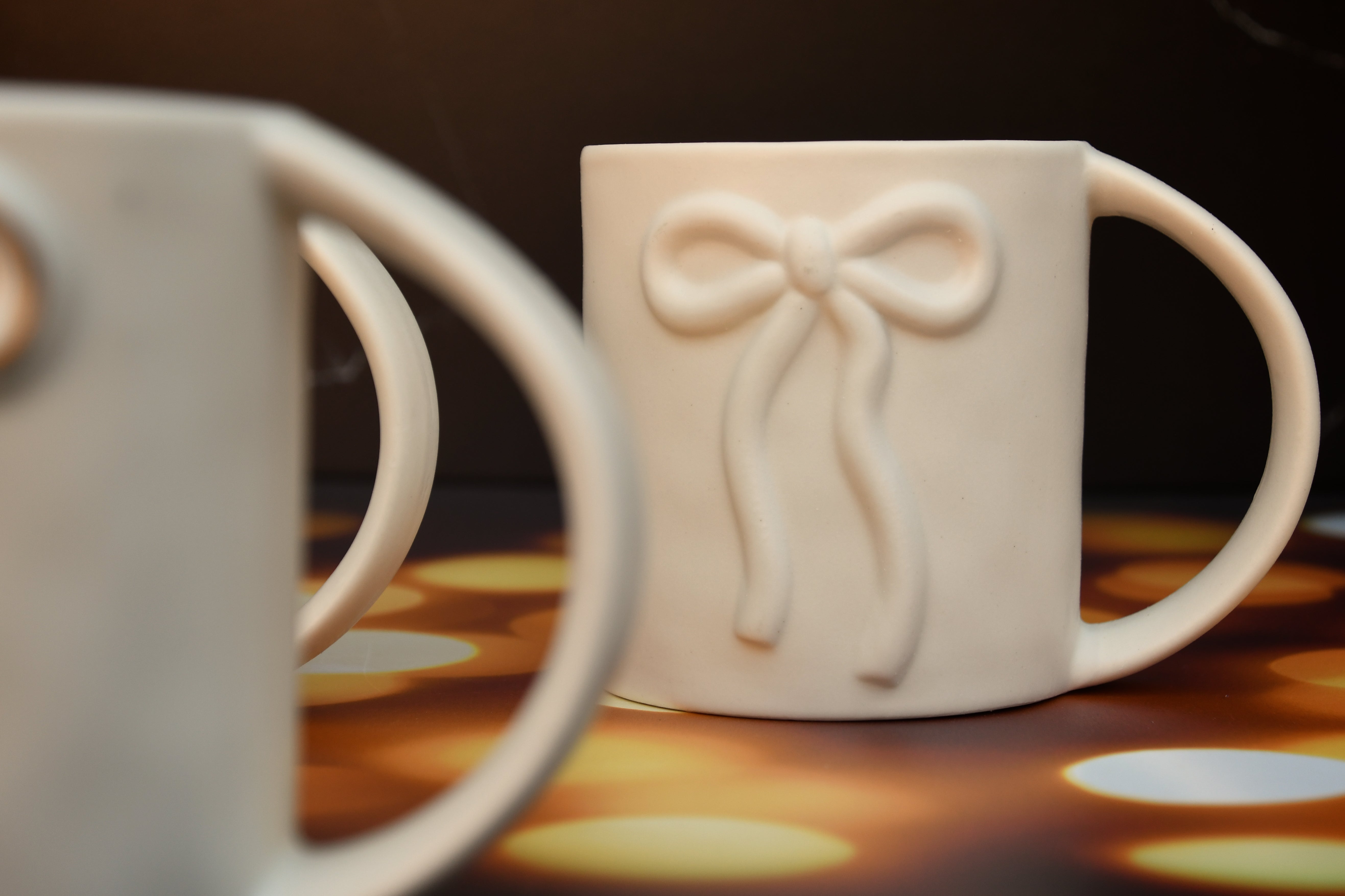 White ceramic mug with raised bow design. 16oz.