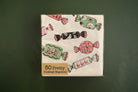 A pack of 50 Pretty Cocktail Napkins featuring a Halloween candy print, shown on a dark green background.
