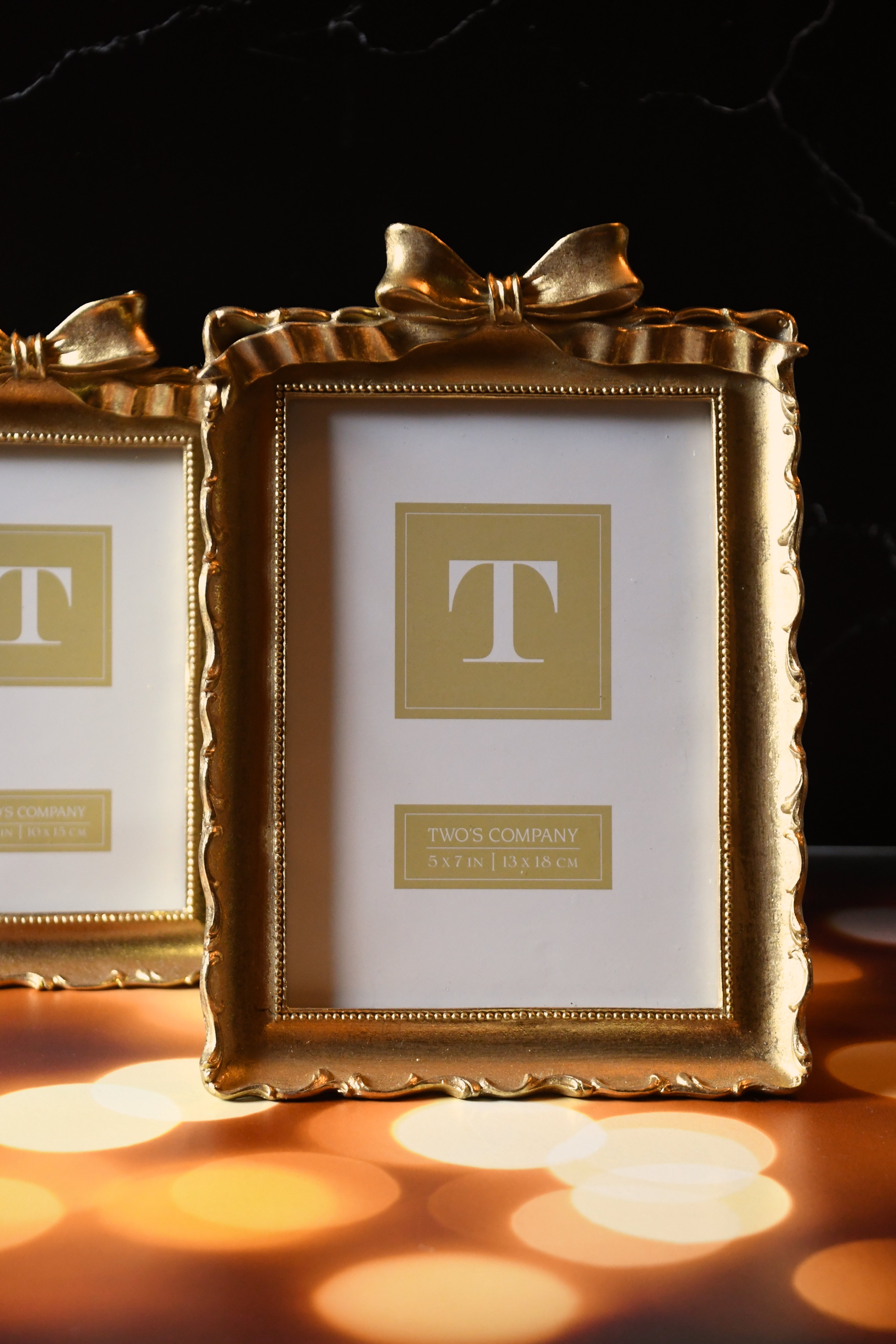 Gold picture frame with a bow on a dark background