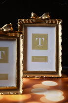 Two gold picture frames with a bow on a dark background