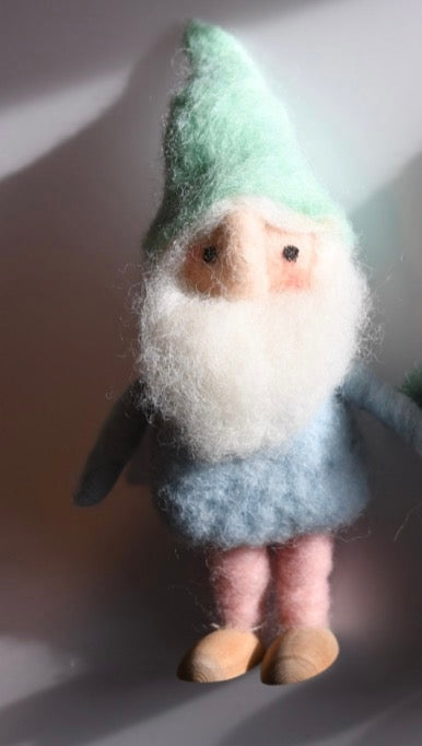 Felted gnome figurine with green hat and gray outfit on a neutral background