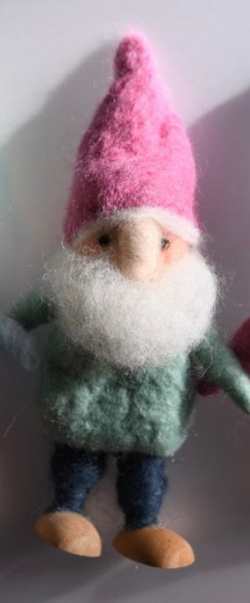 Small gnome figurine with a pink hat on a plain background