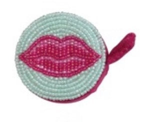 Circular object with beaded design and pink lips on a white background