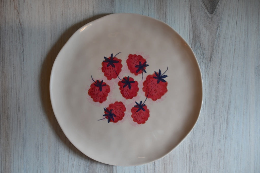 Beige plate with red floral patterns on a wooden surface