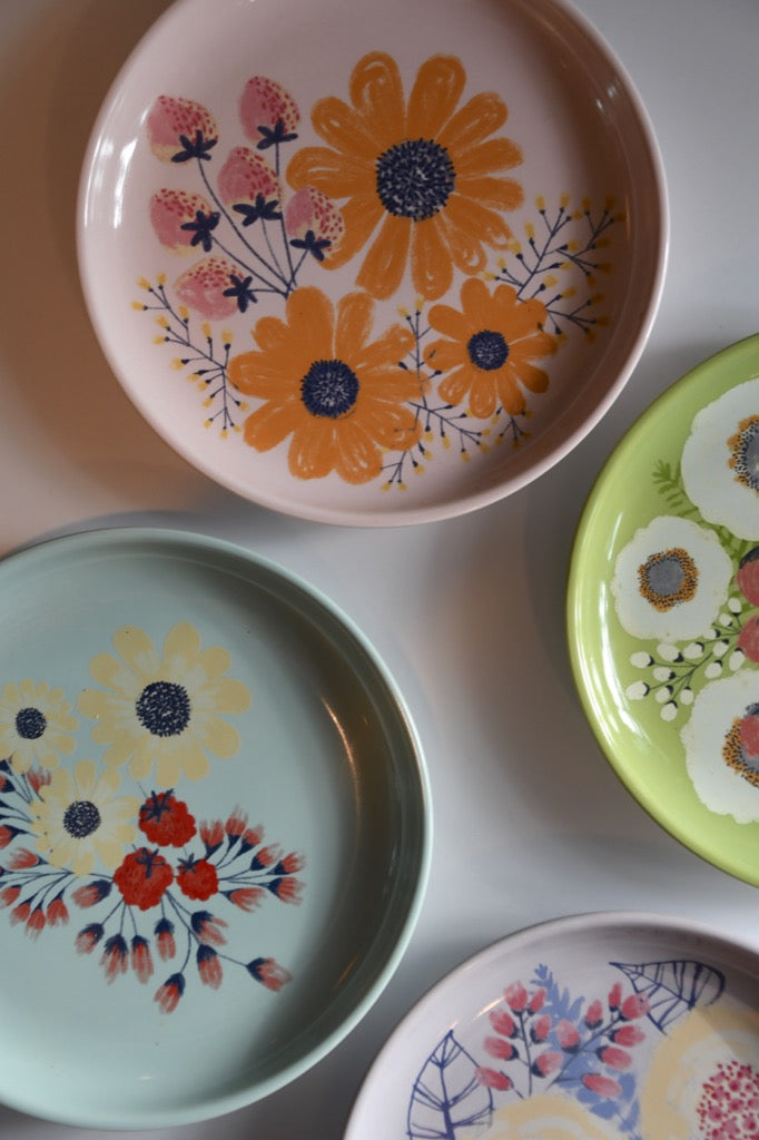 Set of colorful ceramic plates with floral designs on a white surface