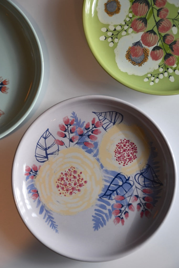 Three ceramic plates with floral designs on a light background
