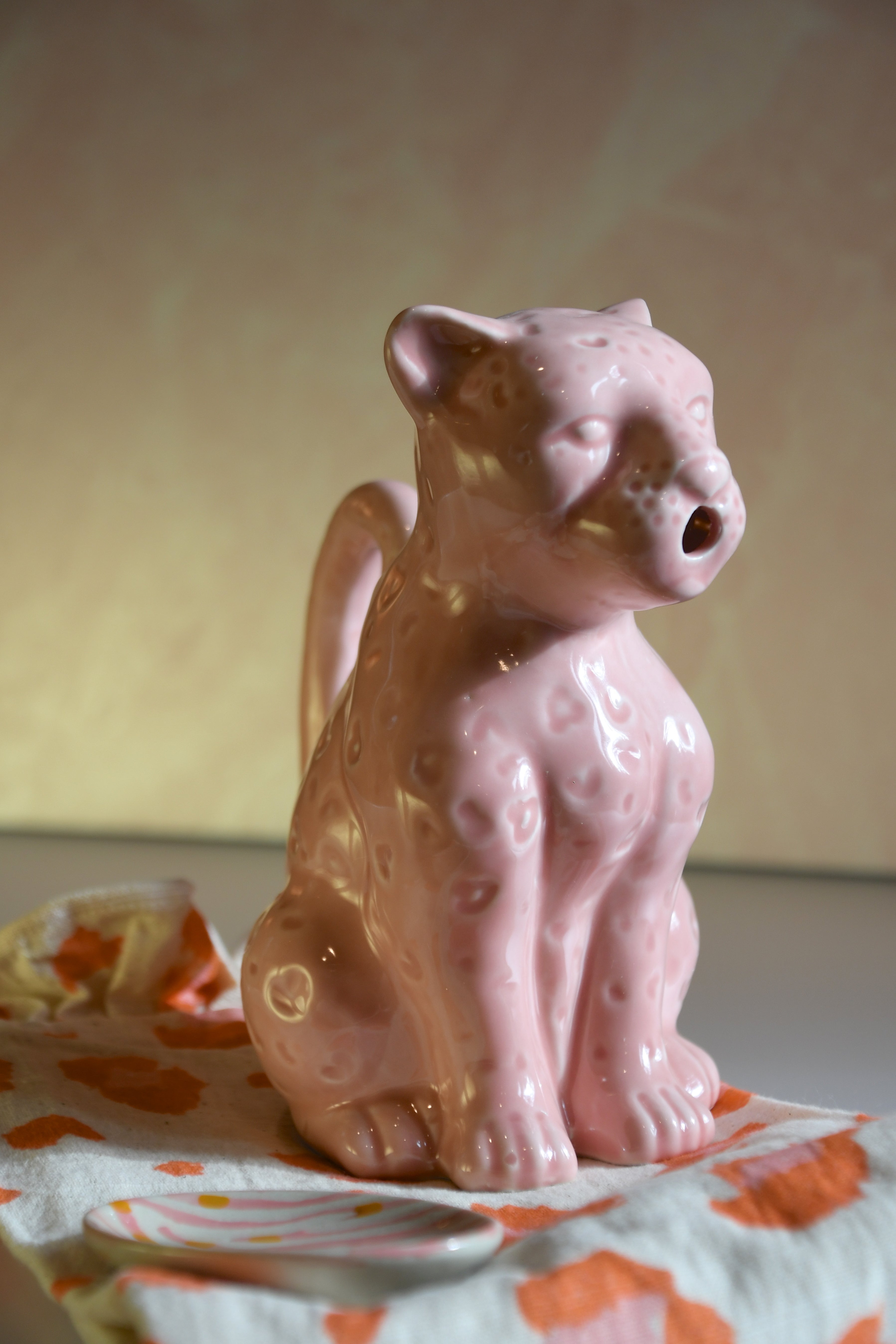 Pink ceramic panther figurine on a patterned surface with a neutral background
