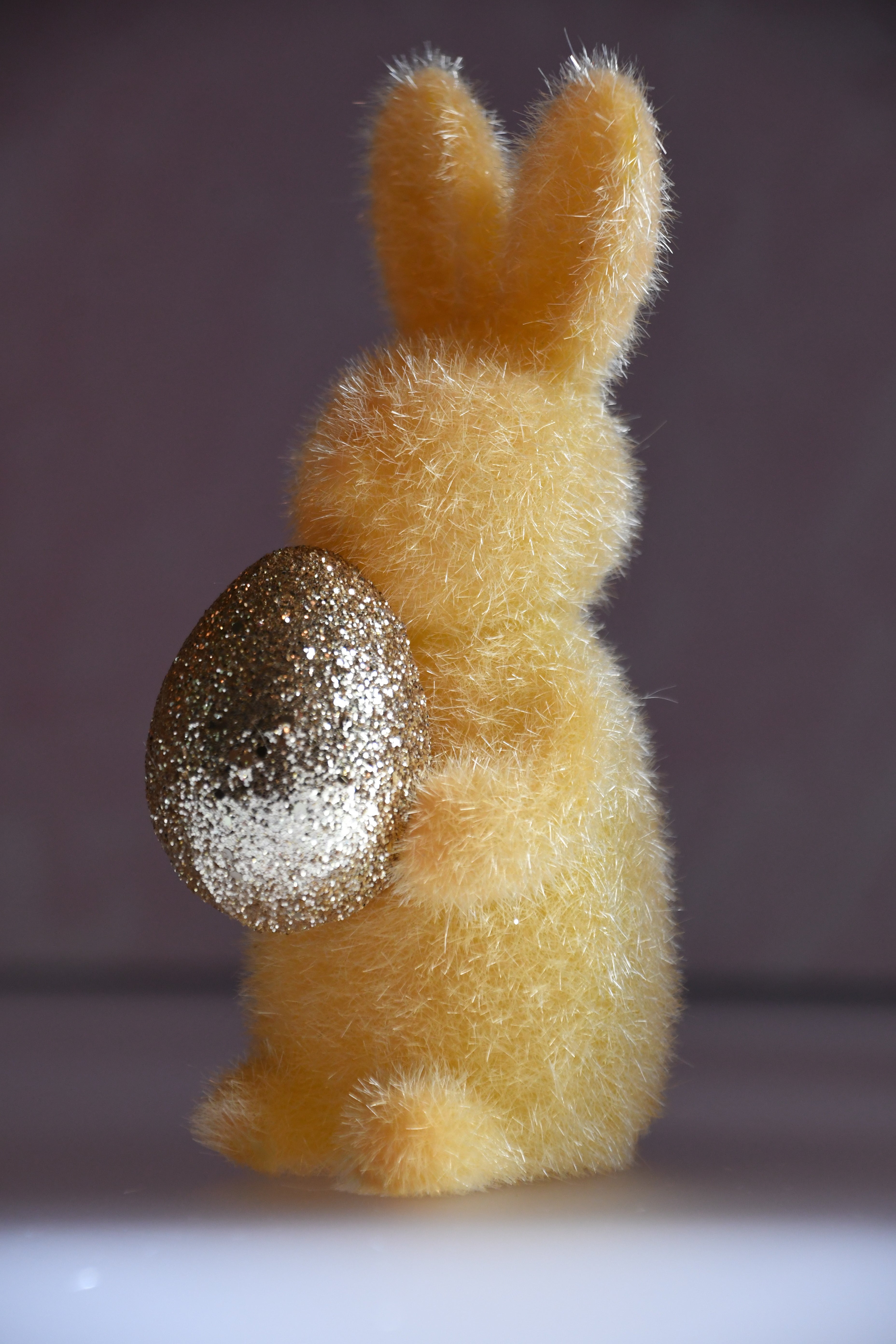 Plush bunny with a glittery egg on a plain background