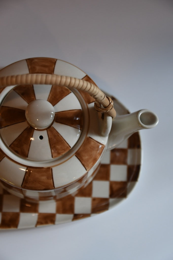 Teapot with brown and white checkered pattern on a plain background