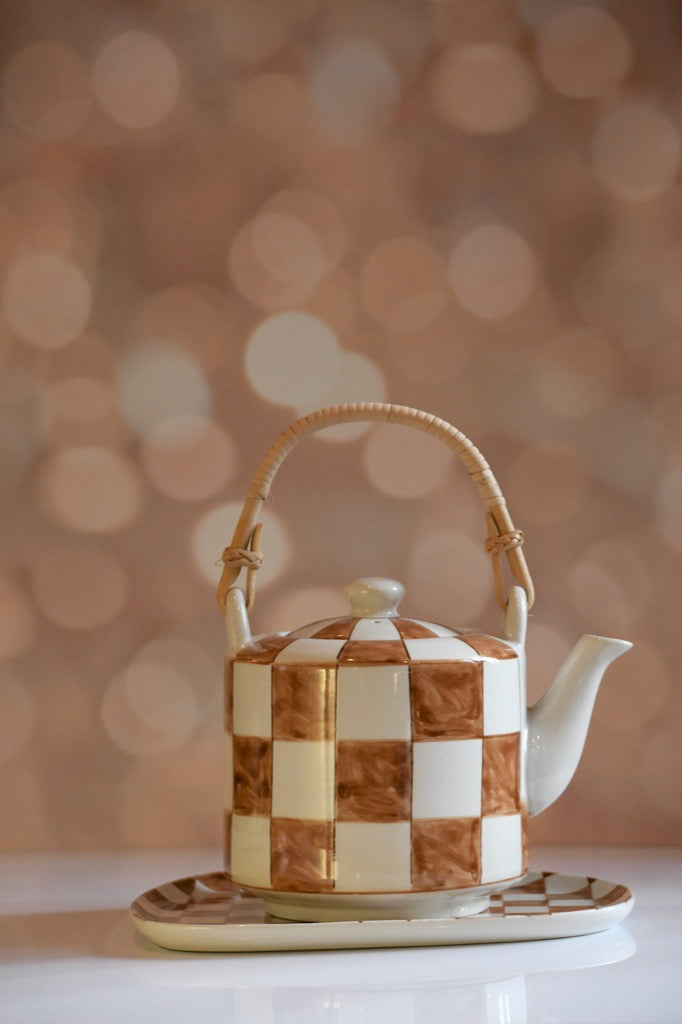 Checkered teapot with a wooden handle on a blurred background