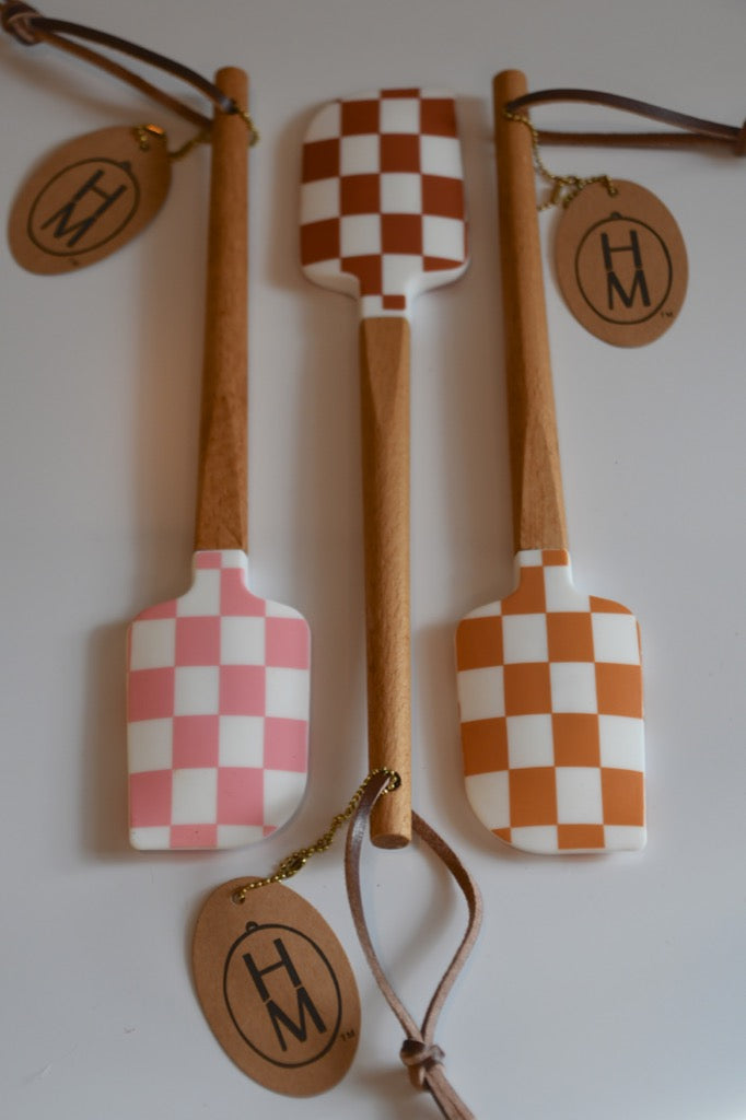Set of three wooden spatulas with checkered patterns and 'HM' branding on a white background