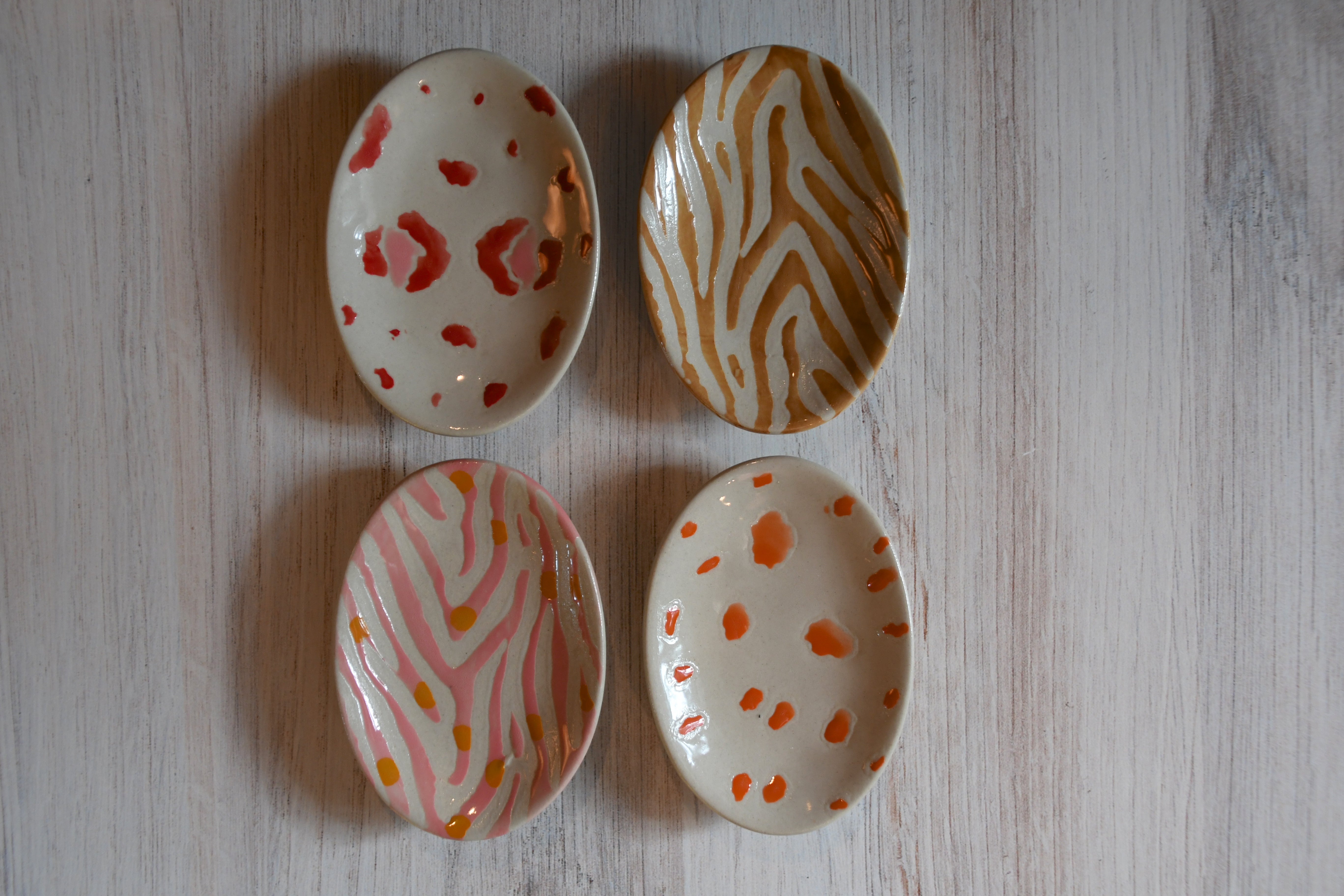 Four ceramic dishes with different patterns on a light wooden surface