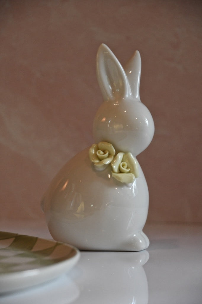 White ceramic bunny with a yellow rose on a pink background