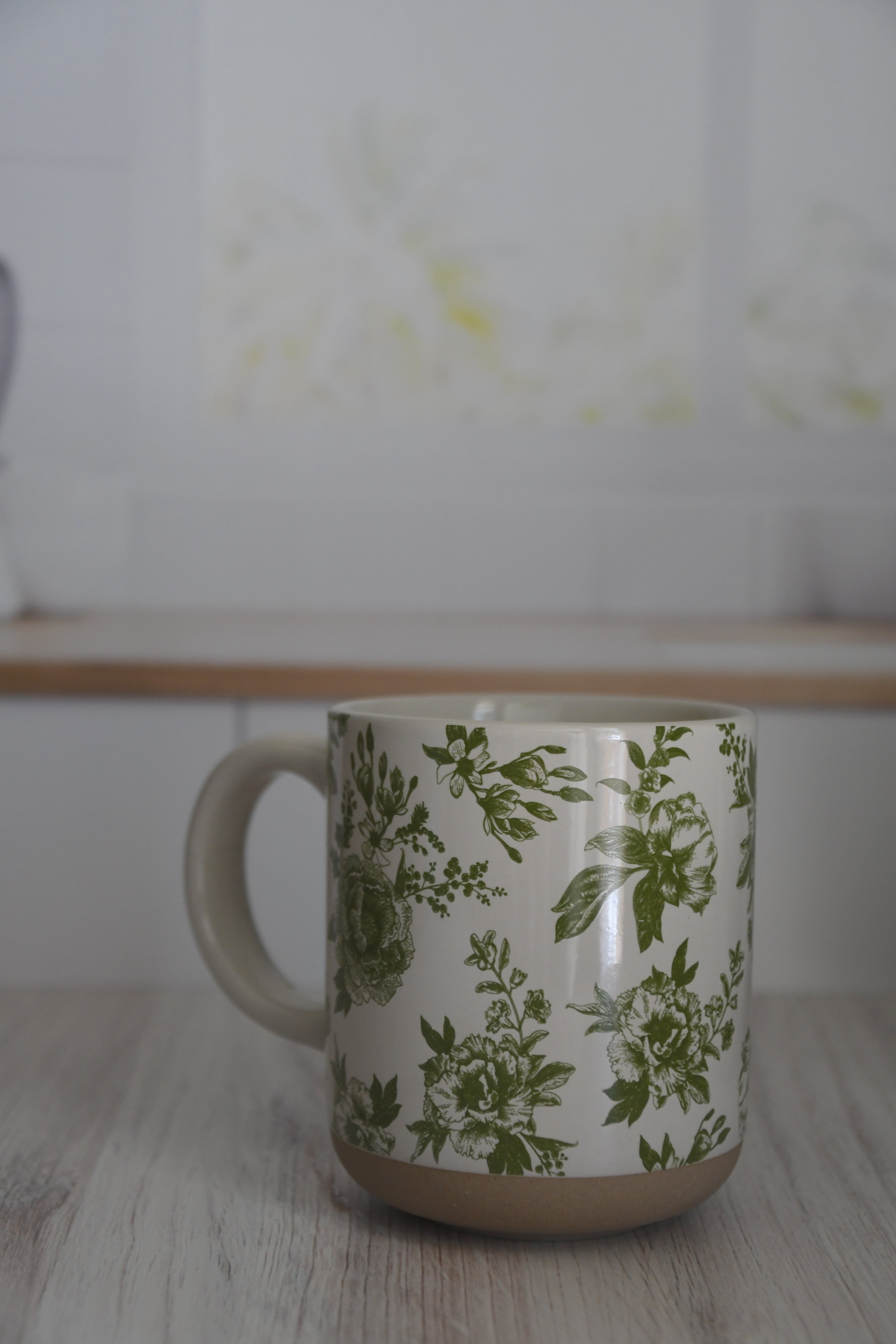Mug with green floral pattern on a wooden surface
