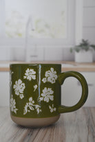 Green mug with white floral patterns on a wooden surface